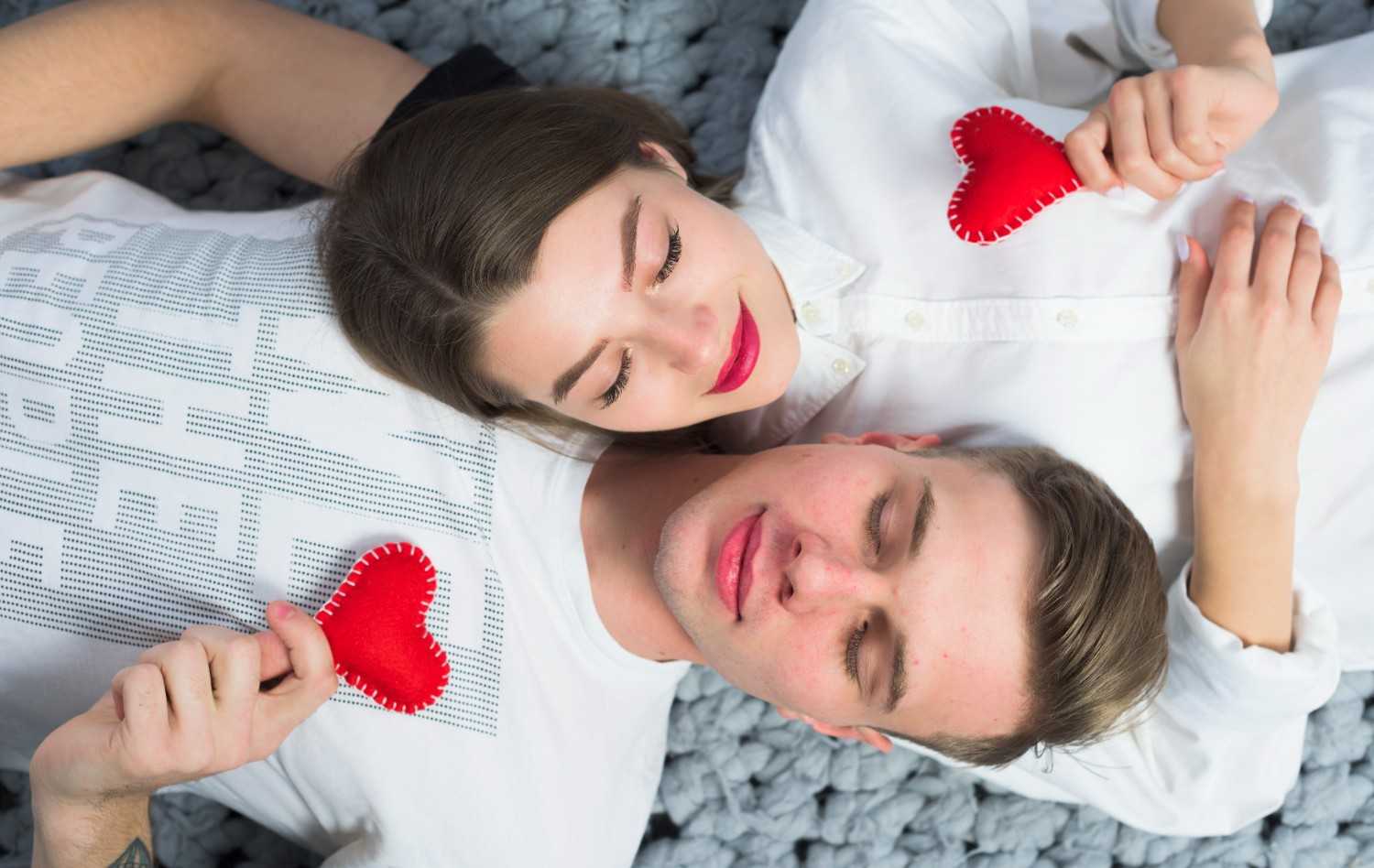 The couple lies with small toy hearts, symbolizing the rules of dating and modern etiquette