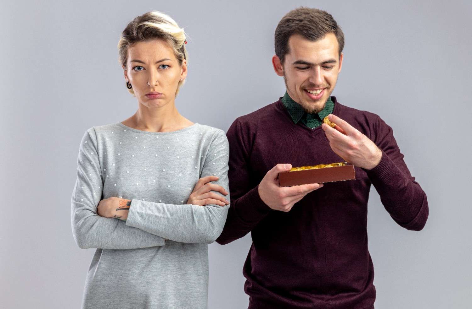 Unpleased girl standing next to guy with box of candies, symbolizing the difference between dating rules and modern etiquette for men and women